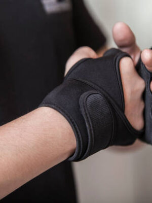 Man's hands put on sports gloves for a gym