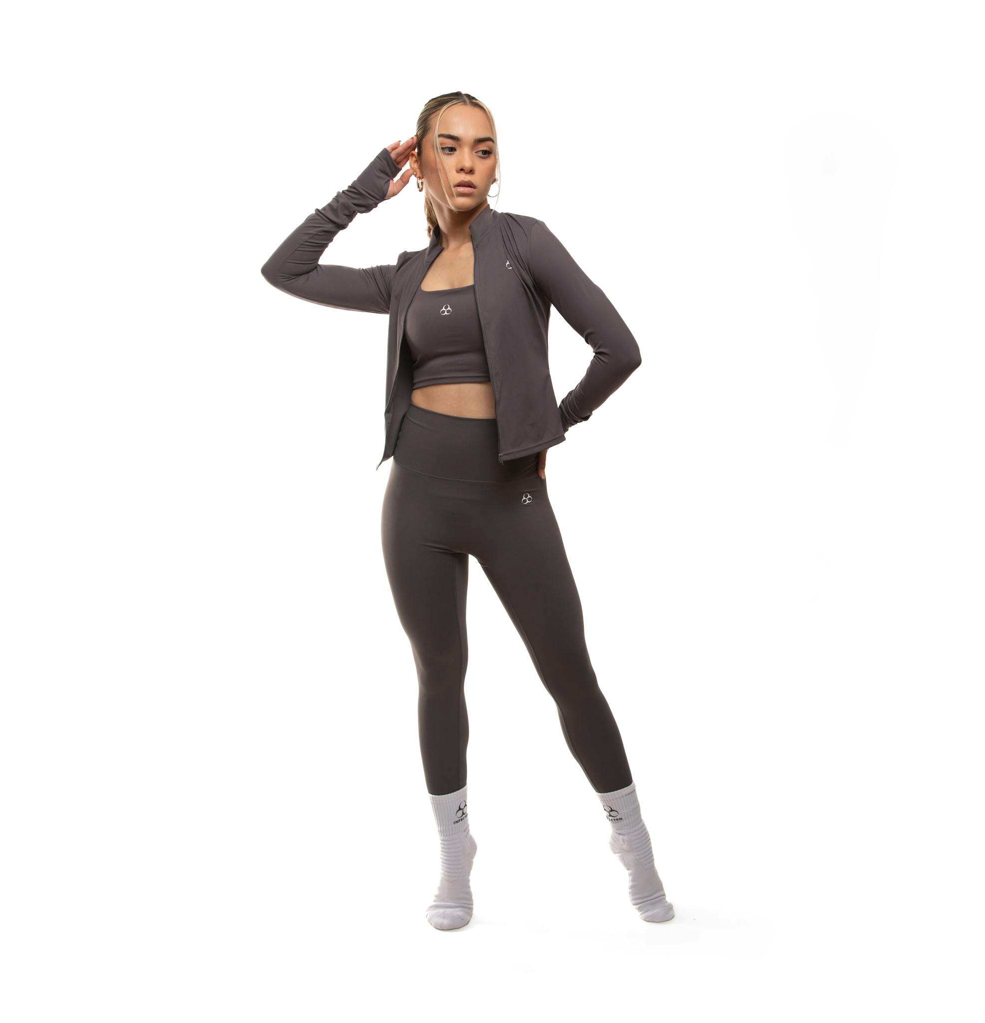 Woman in dark athletic wear striking a pose in a clean studio setting.